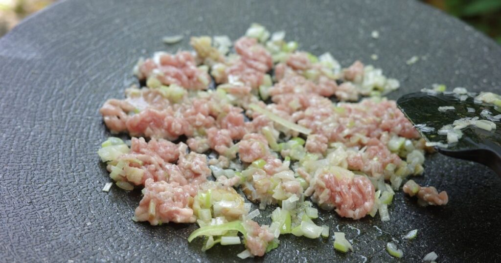 ひき肉とねぎ・しょうが・にんにくを炒め合わせる