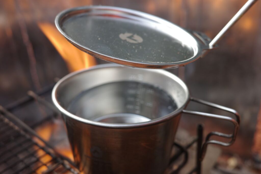 焚き火でシェラカップを使ってお湯を沸かす
