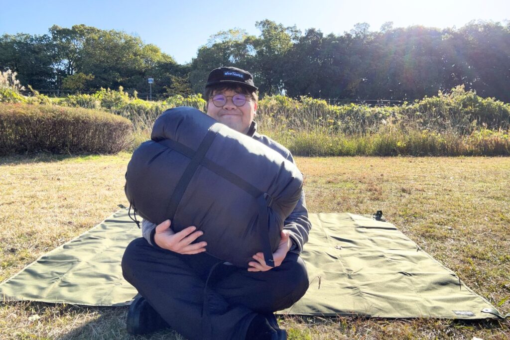 ベアーズロック「-30℃寝袋 FX-503W」を抱えるたなそう